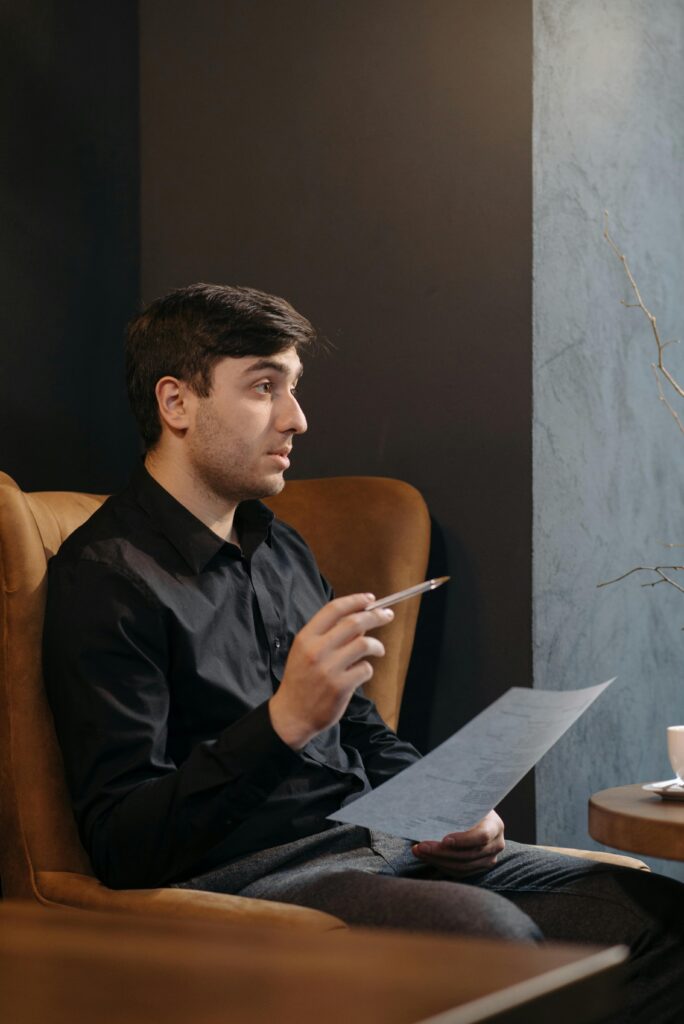 A man in a café holding a document, appearing engaged in conversation.